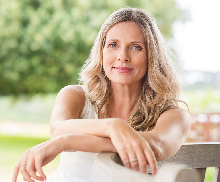 Happy mature woman relaxing on bench.